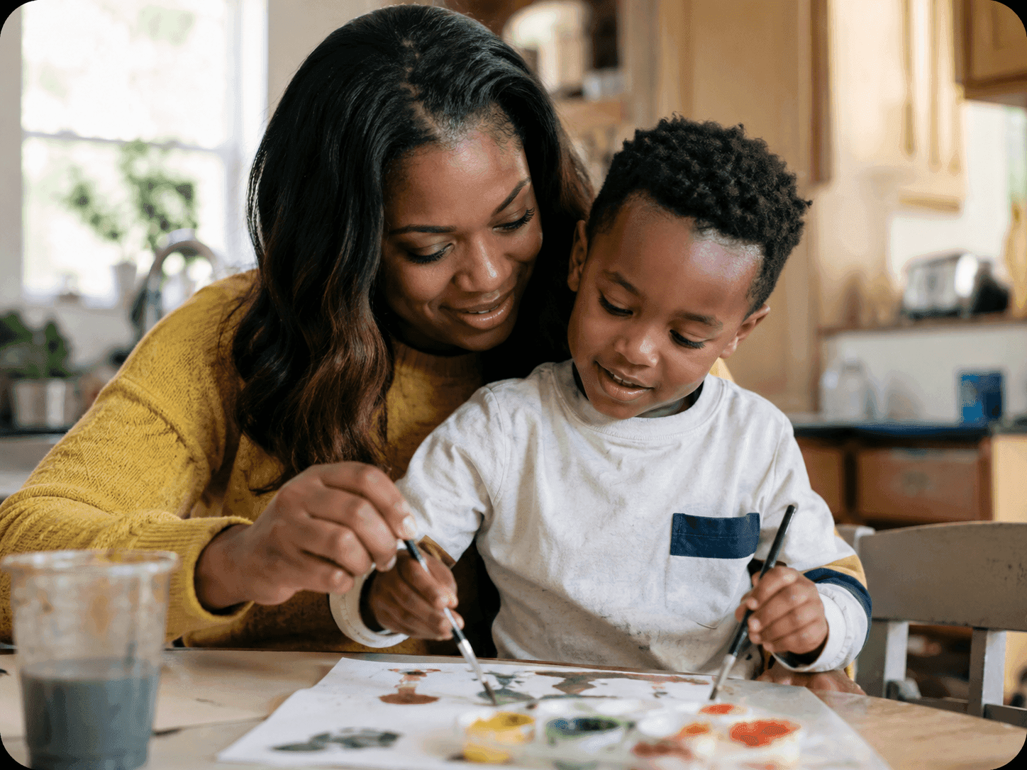 A mother and son painting with watercolors together at a table
