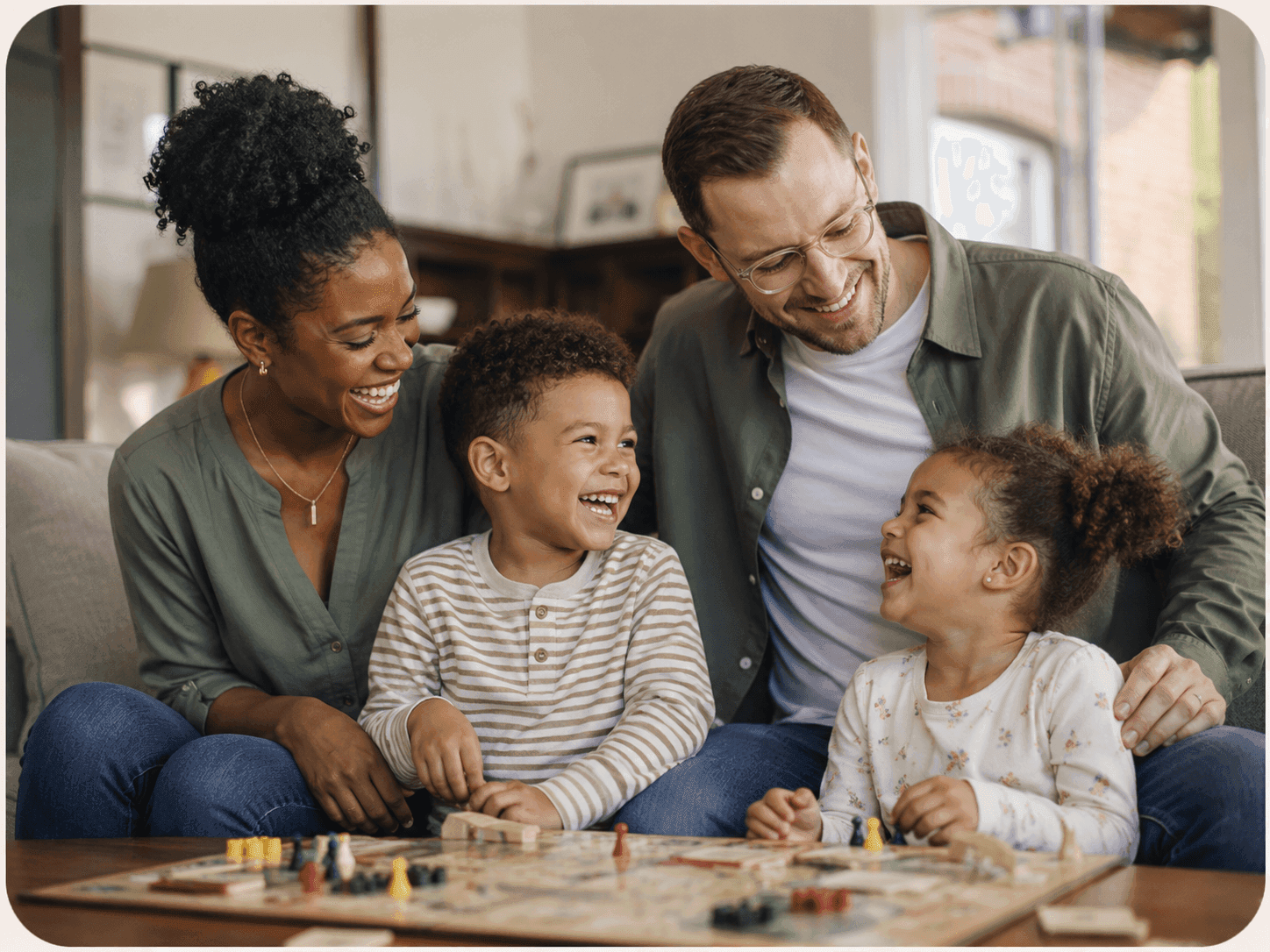 Two parents and their two children laughing together over a board game