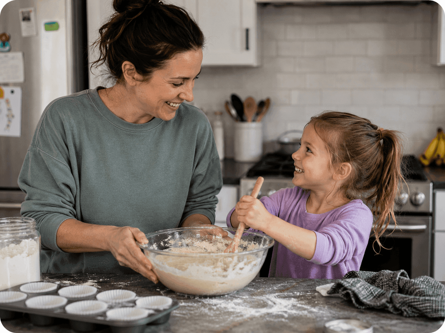 A mother and her young daughter mixing batter together in the kitchen